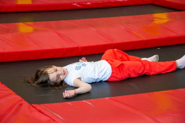 Mutlu kız trambolinde zıplarken eğleniyor. Sporcu kız trambolinde zıplıyor. Trambolinde zıplayan bir kızın açık hava çekimi, evde zıplamaktan hoşlanıyor. Mutlu yaz tatilleri. Yüksek kalite fotoğraf