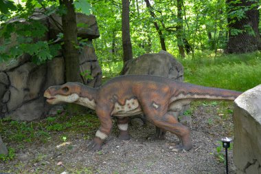Jurasik dünyadan bir sahnede bir dinazor gösteriliyor. Parktaki dinozor modeli. Dev Tyrannosaurus parktaki bir sergide.