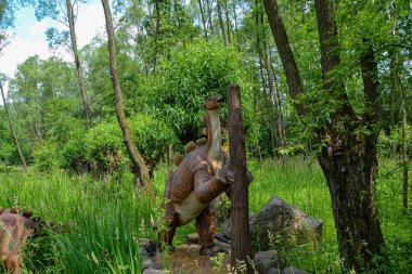 Jurasik dünyadan bir sahnede bir dinazor gösteriliyor. Parktaki dinozor modeli. Dev Tyrannosaurus parktaki bir sergide.