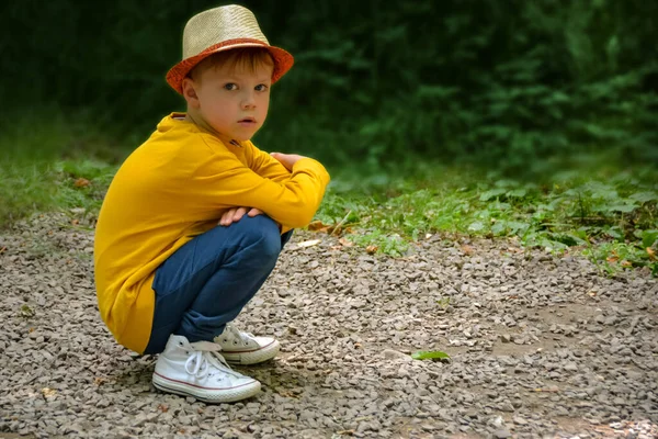Ein Junge Mit Gelbem Hemd Und Hut Kniet Auf Einer — Stockfoto