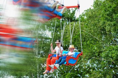 Çocuklar dönme dolapta zincirlerle, lunaparkta kayak broşürleriyle eğleniyorlar. Mutlu çocuklar, güneşli bir günde ikizler dışarıda eğleniyor. Yüksek kalite fotoğraf