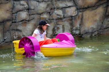 Çocuk su kayığı oynuyor. Yumuşak odaklanma. Küçük bir kız, tatil köyündeki bir havuzda renkli bir tekneye biniyor. Yüksek kalite fotoğraf