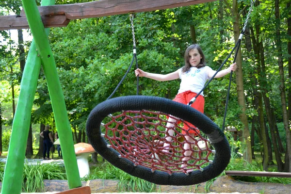 幸せな小さな子供の女の子が遊び 自然公園のスイングに座って閉じます 夏の公園でスイングに10代の女の子 高品質の写真 — ストック写真