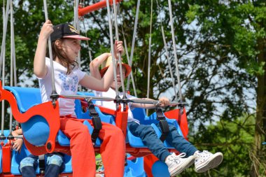 Çocuklar dönme dolapta zincirlerle, lunaparkta kayak broşürleriyle eğleniyorlar. Mutlu çocuklar, güneşli bir günde ikizler dışarıda eğleniyor. Yüksek kalite fotoğraf