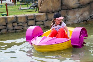 Çocuk su kayığı oynuyor. Yumuşak odaklanma. Küçük bir kız, tatil köyündeki bir havuzda renkli bir tekneye biniyor. Yüksek kalite fotoğraf