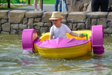 Çocuk su kayığı oynuyor. Yumuşak odaklanma. Küçük bir kız, tatil köyündeki bir havuzda renkli bir tekneye biniyor. Yüksek kalite fotoğraf