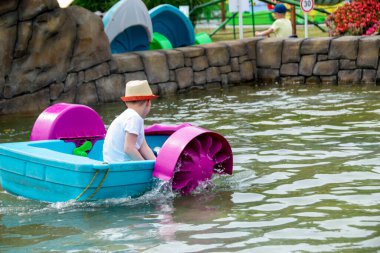 Çocuk su kayığı oynuyor. Yumuşak odaklanma. Küçük bir kız, tatil köyündeki bir havuzda renkli bir tekneye biniyor. Yüksek kalite fotoğraf