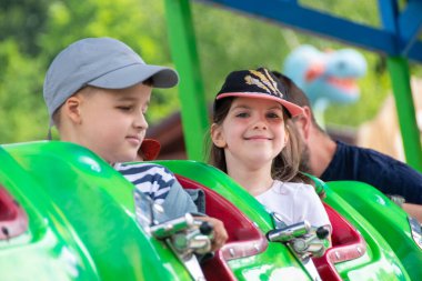 Çocuklar dönme dolapta zincirlerle, lunaparkta kayak broşürleriyle eğleniyorlar. Mutlu çocuklar, güneşli bir günde ikizler dışarıda eğleniyor. Yüksek kalite fotoğraf