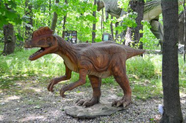 Jurasik dünyadan bir sahnede bir dinazor gösteriliyor. Parktaki dinozor modeli. Dev Tyrannosaurus parktaki bir sergide.