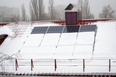 Güneş panelleri karla kaplı. Güneşli bir günde kış mevsiminde evin çatısına fotovoltaik elektrik kurulumu. Soğuk havada alternatif enerji üretimi. Yüksek kalite fotoğraf
