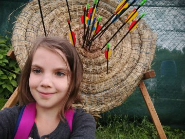 Archery for child. Little girl with bow and arrow. Kids shoot on tropical island. Target on outdoor shooting range. Archer club for young children. Healthy summer activity. High quality photo