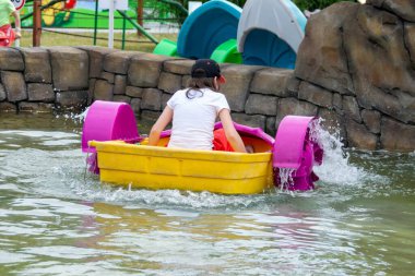 Çocuk su kayığı oynuyor. Yumuşak odaklanma. Küçük bir kız, tatil köyündeki bir havuzda renkli bir tekneye biniyor. Yüksek kalite fotoğraf