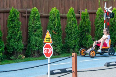 Yürüyen çocuk trafik kurallarını çocuk için bir trafik parkında öğreniyor. Kaliteli bir fotoğraf. Her şeyini verirken yüzünde kararlı bir ifade var. Yüksek kalite fotoğraf