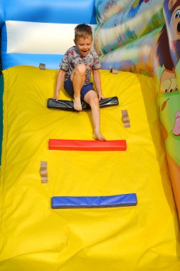 Trambolinde oynayan neşeli küçük çocuk. Parkta oynayan, kot takım elbiseli, sarı saçlı beyaz bir çocuk. Yüksek kalite fotoğraf