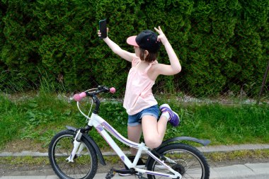 Genç kız bisikletçi yaz ormanı patikasında güneşin doğuşunun tadını çıkarıyor. Bisikletli kasklı mutlu küçük bir kızın yakın plan portresi. Yüksek kalite fotoğraf