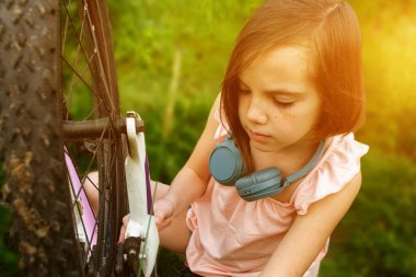Genç kız bisikletçi yaz ormanı patikasında güneşin doğuşunun tadını çıkarıyor. Bisikletli kasklı mutlu küçük bir kızın yakın plan portresi. Yüksek kalite fotoğraf