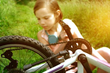 Genç kız bisikletçi yaz ormanı patikasında güneşin doğuşunun tadını çıkarıyor. Bisikletli kasklı mutlu küçük bir kızın yakın plan portresi. Yüksek kalite fotoğraf