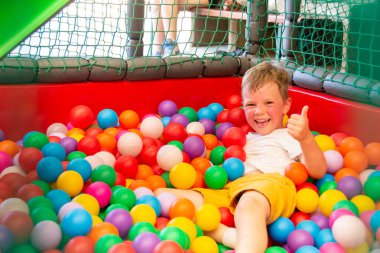 Çocuk oyun bahçesinde, çocukların labirentinde top oynuyor. Çok renkli toplar, yumuşak duvarlar ve çocuklar için zemin. Yüksek kalite fotoğraf