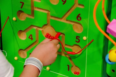 Çocuk Montessori oyunu oynuyor. Çocuk tahta oyuncak ayırıcı topluyor. Çok renkli geometrik şekiller, daire, kare, üçgen, dikdörtgen. Erken çocukluk gelişimi. Yüksek kalite fotoğraf