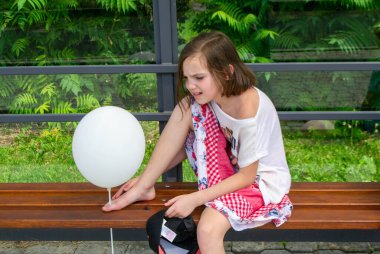 Kız portresi yüzünü helyum balonunun arkasına saklar. Kıvırcık saçlı, balonu yüzüne karşı doğal arka plan, tatil ve kutlamaya karşı tutan tatlı bir kız. Yüksek kalite fotoğraf