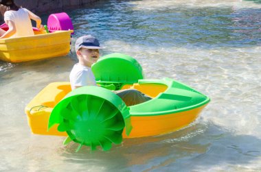 Çocuk su kayığı oynuyor. Yumuşak odaklanma. Küçük bir kız, tatil köyündeki bir havuzda renkli bir tekneye biniyor. Yüksek kalite fotoğraf. 