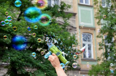 Image of toy gun shooting bubbles in the air on outdoors park. High quality photo clipart