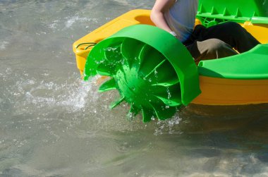 Çocuk su kayığı oynuyor. Yumuşak odaklanma. Küçük bir kız, tatil köyündeki bir havuzda renkli bir tekneye biniyor. Yüksek kalite fotoğraf. 