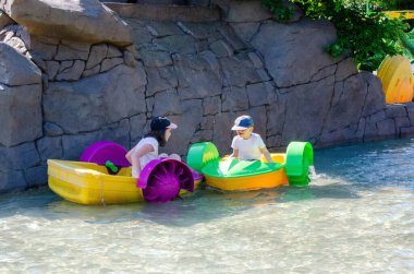 Çocuk su kayığı oynuyor. Yumuşak odaklanma. Küçük bir kız, tatil köyündeki bir havuzda renkli bir tekneye biniyor. Yüksek kalite fotoğraf. 