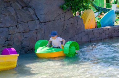 Çocuk su kayığı oynuyor. Yumuşak odaklanma. Küçük bir kız, tatil köyündeki bir havuzda renkli bir tekneye biniyor. Yüksek kalite fotoğraf. 