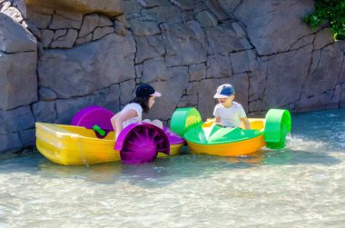 Çocuk su kayığı oynuyor. Yumuşak odaklanma. Küçük bir kız, tatil köyündeki bir havuzda renkli bir tekneye biniyor. Yüksek kalite fotoğraf. 