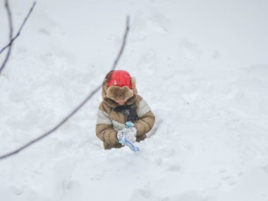 Oğlan çocuğu güneşli bir kış gününde kar kalesinde oynarken eğleniyor. Soğuk hava için kış retro giysileri. Yüksek kalite fotoğraf