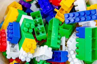 Renkli gökkuşağı plastik oyuncak tuğlaları beyaza izole edilmiş. Eğitim konsepti. Mavi, kırmızı ve sarı lego oyuncaklar arka planda. Yüksek kalite fotoğraf