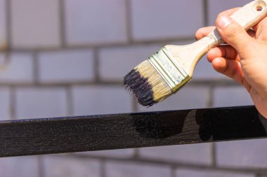 Kara metal fırçayla resim yapan bir kız. Çatıyı boyuyor. Seçici odak