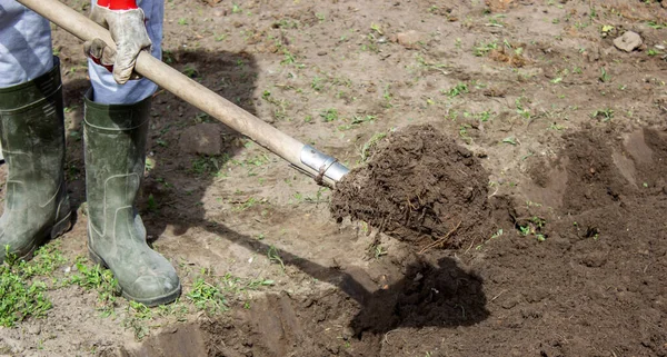 Bahçesinde bahçe aletleri olan lastik çizmeli çiftçi, seçici odaklı.