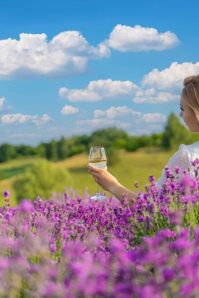 stock image the girl holds a glass of wine on the background of a lavender field. Selective focus. Nature