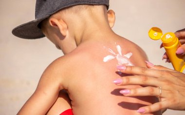 Annem mavi sırtına güneş kremi sürüyor. Seçici odak