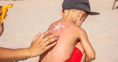 Annem mavi sırtına güneş kremi sürüyor. Seçici odak