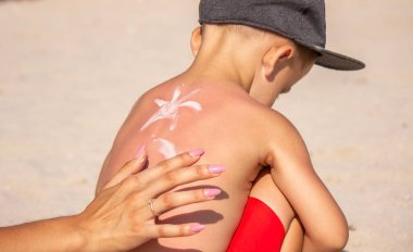 Annem mavi sırtına güneş kremi sürüyor. Seçici odak