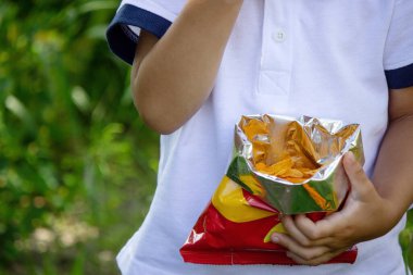 Küçük çocuk patates cipsini paketten yiyor. Seçici odak