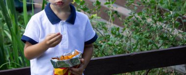 Küçük çocuk patates cipsini paketten yiyor. Seçici odak