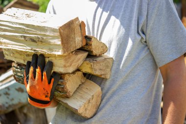 Bir adam elinde bir sürü doğranmış odun tutar. Seçici odak