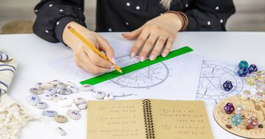 Woman astrologer draws a natal chart. Selective focus. People.