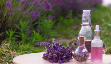 jars with lavender oil, lavender flowers, on the background of a lavender field. Selective focus clipart