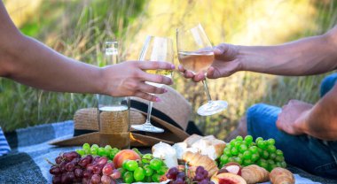 Aşıklar piknikte beyaz şarap içer. Seçici odaklanma. Doğa