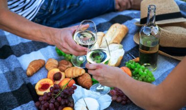 Aşıklar piknikte beyaz şarap içer. Seçici odaklanma. Doğa