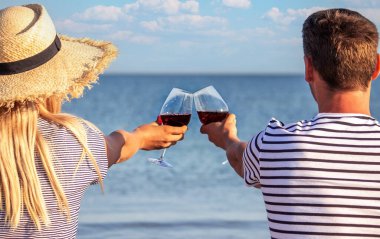 Deniz kenarında şarap içen romantik bir çift. Seçici odak