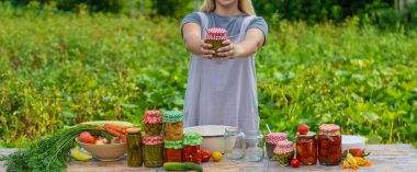 A woman preserves vegetables in jars. Selective focus. Food.