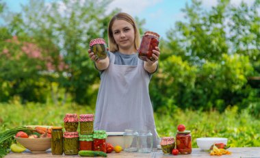 A woman preserves vegetables in jars. Selective focus. Food.