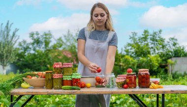 A woman preserves vegetables in jars. Selective focus. Food.