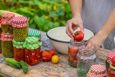 A woman preserves vegetables in jars. Selective focus. Food.